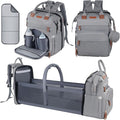 A gray diaper bag backpack shown in multiple configurations on a white background: closed from the front, with the front pocket opened to show interior pockets, and transformed into a bassinet or changing pad with side storage. A small inset at top left shows a matching gray cover or liner.